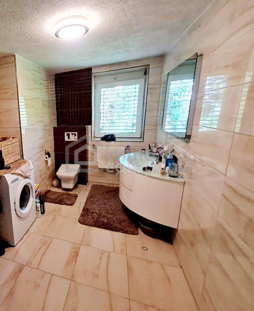 Modernes Badezimmer mit Fliesen, Waschmaschine, Toilette und Waschbecken.