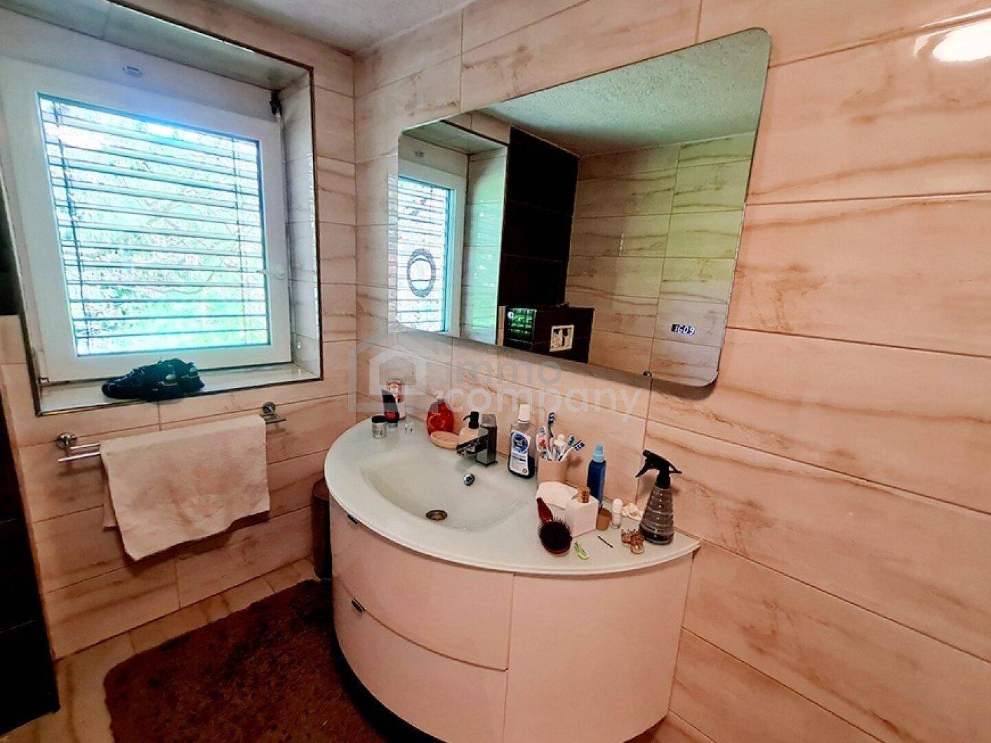 Badezimmer mit modernem Waschbecken, großem Spiegel und Fenster.