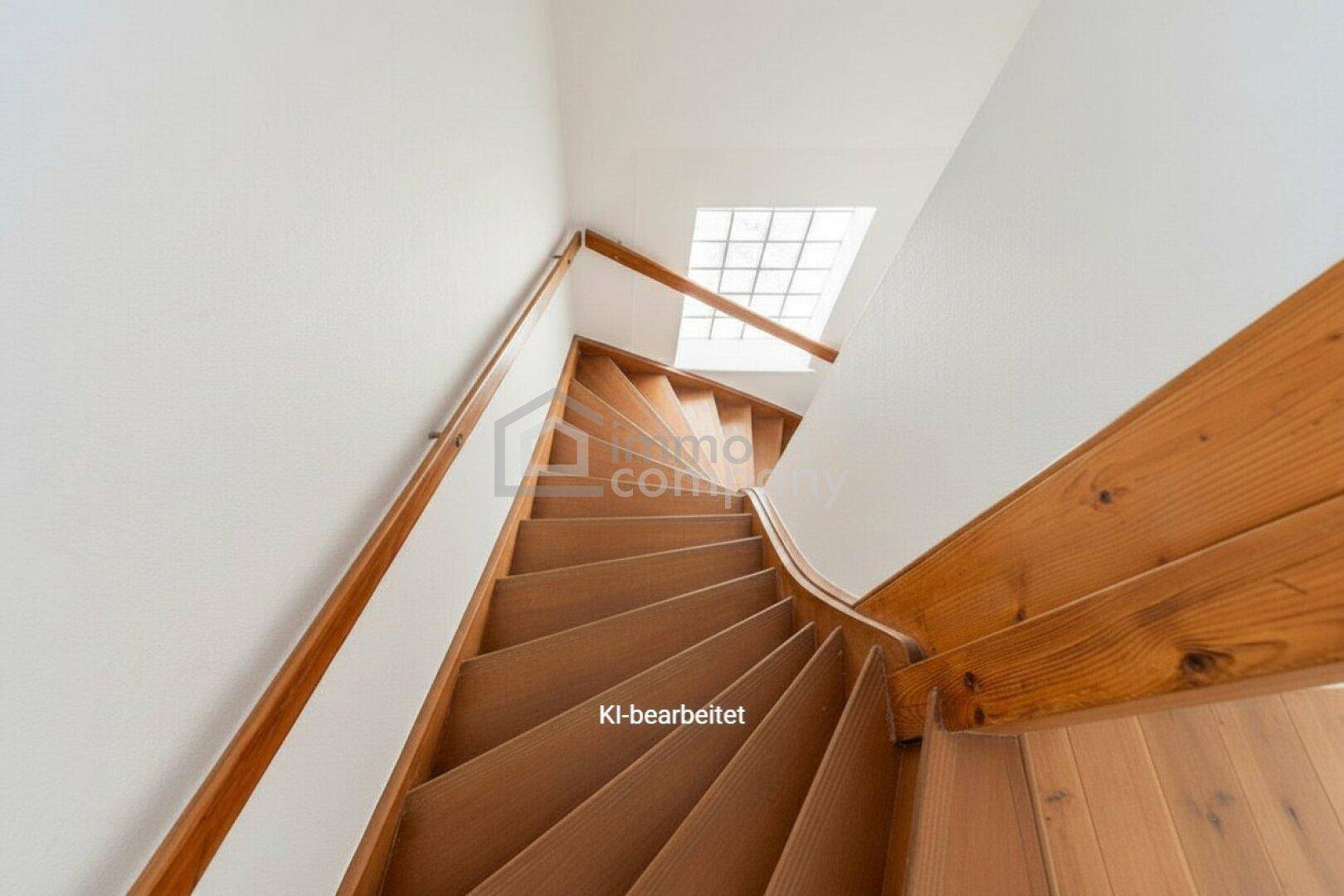 Helle Holztreppe mit Handlauf und Oberlicht, die in die obere Etage des Hauses führt.
