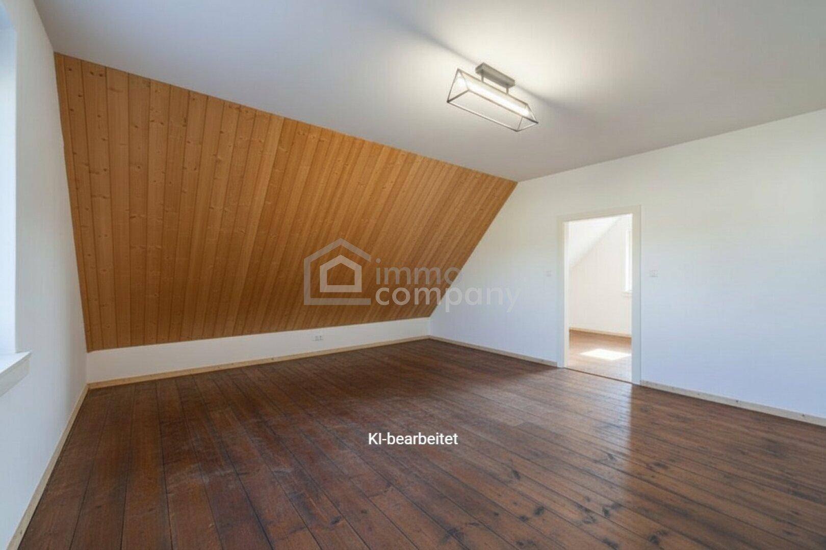 Geräumiges Dachzimmer mit Holzverkleidung an der Schräge und dunklem Holzboden, bereit zur Gestaltung.