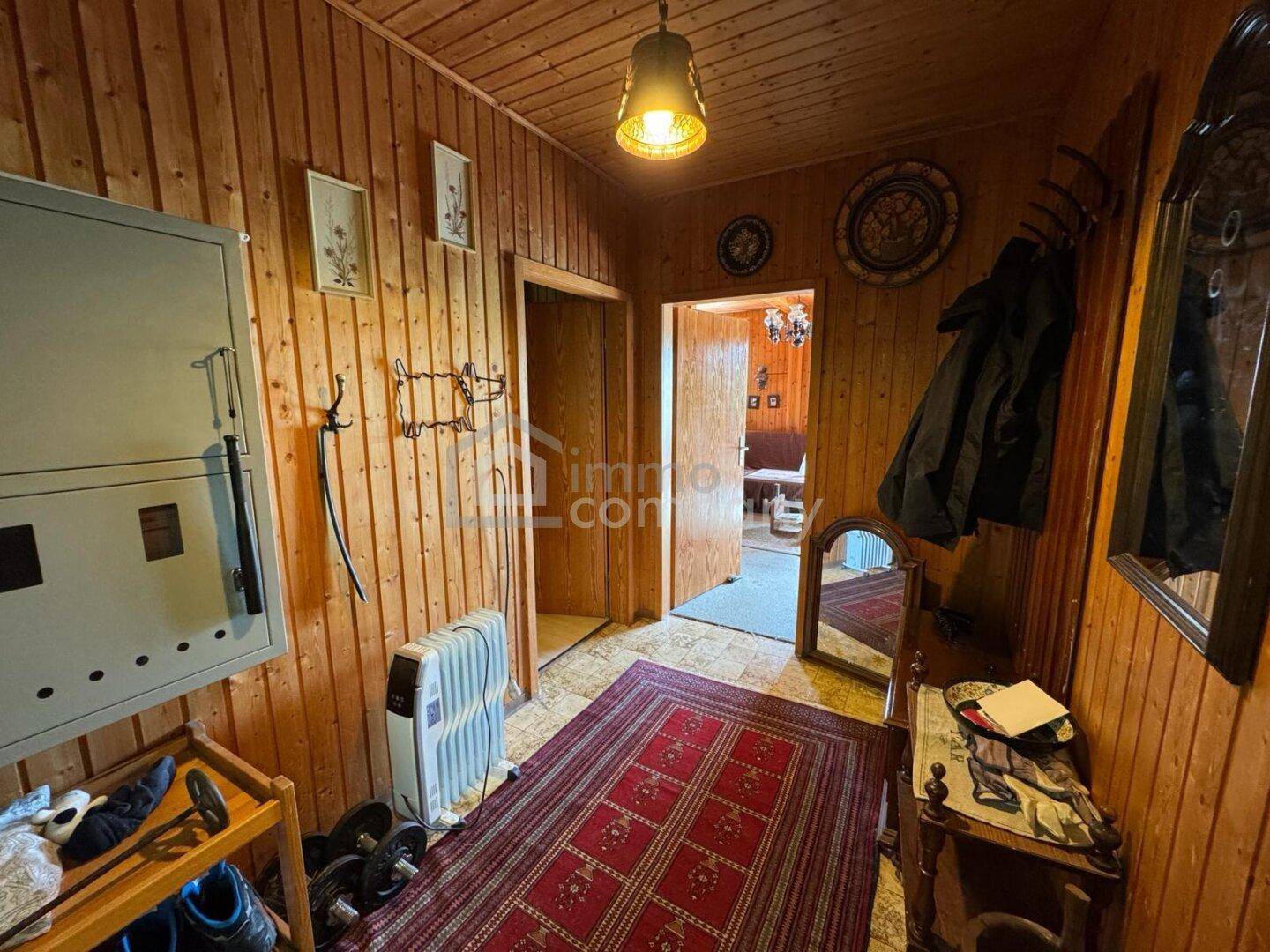 Gemütlicher Eingangsbereich mit Holzvertäfelung, rotem Teppich und traditionellen Dekorationen.