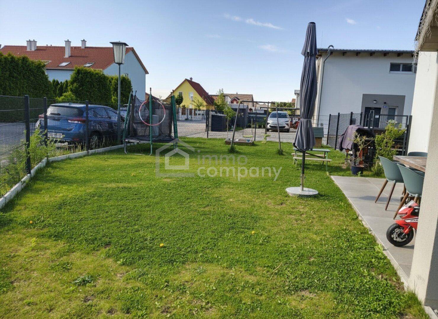 Geräumiger Gartenbereich mit Rasenfläche, Trampolin und Schaukel, ideal für Familienaktivitäten.