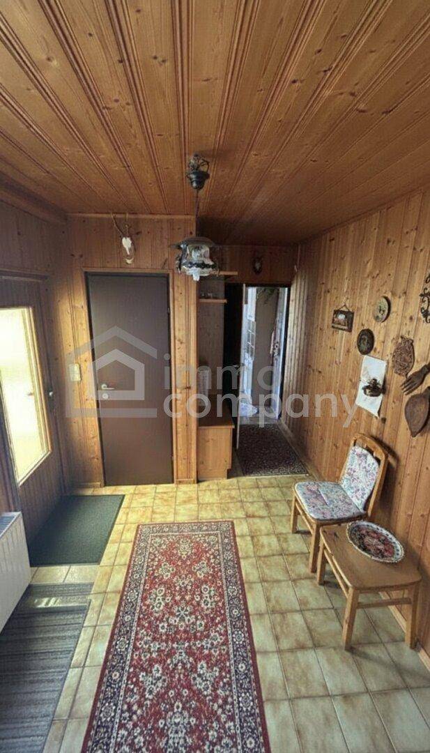 Eingangsbereich mit Holzvertäfelung an Wänden und Decke, Fliesenboden und rustikalen Dekorationen.