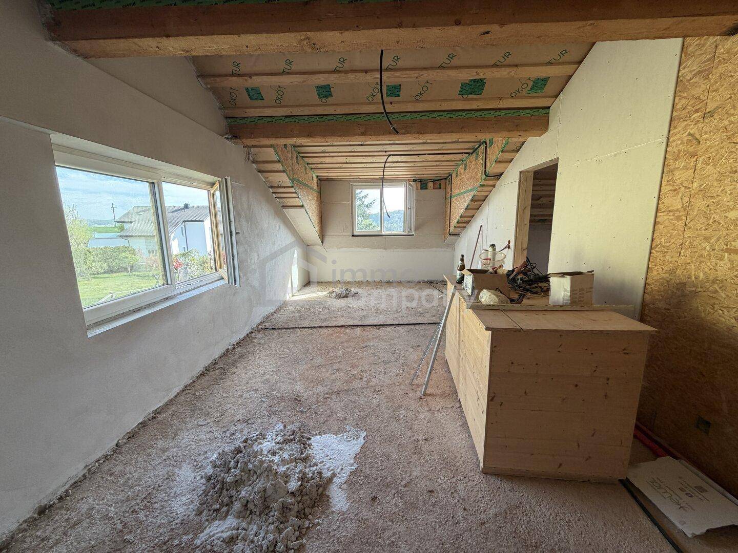 Ausbaufähiges Dachgeschoss mit Fenstern und sichtbarer Holzkonstruktion, bereit für den Innenausbau.
