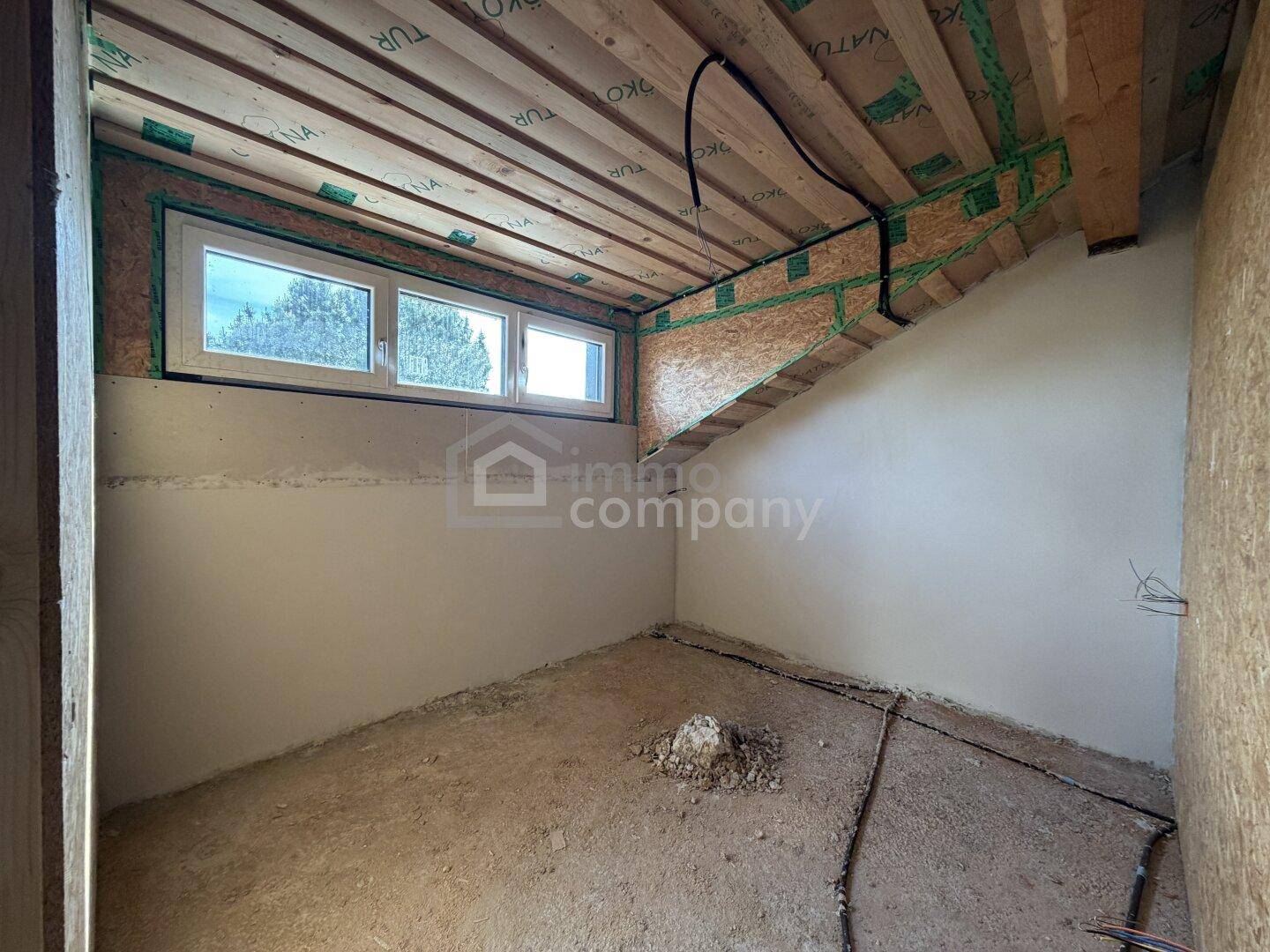Kleiner Raum im Dachgeschoss mit Fenster und sichtbarer Holzkonstruktion, ideal für ein weiteres Zimmer.
