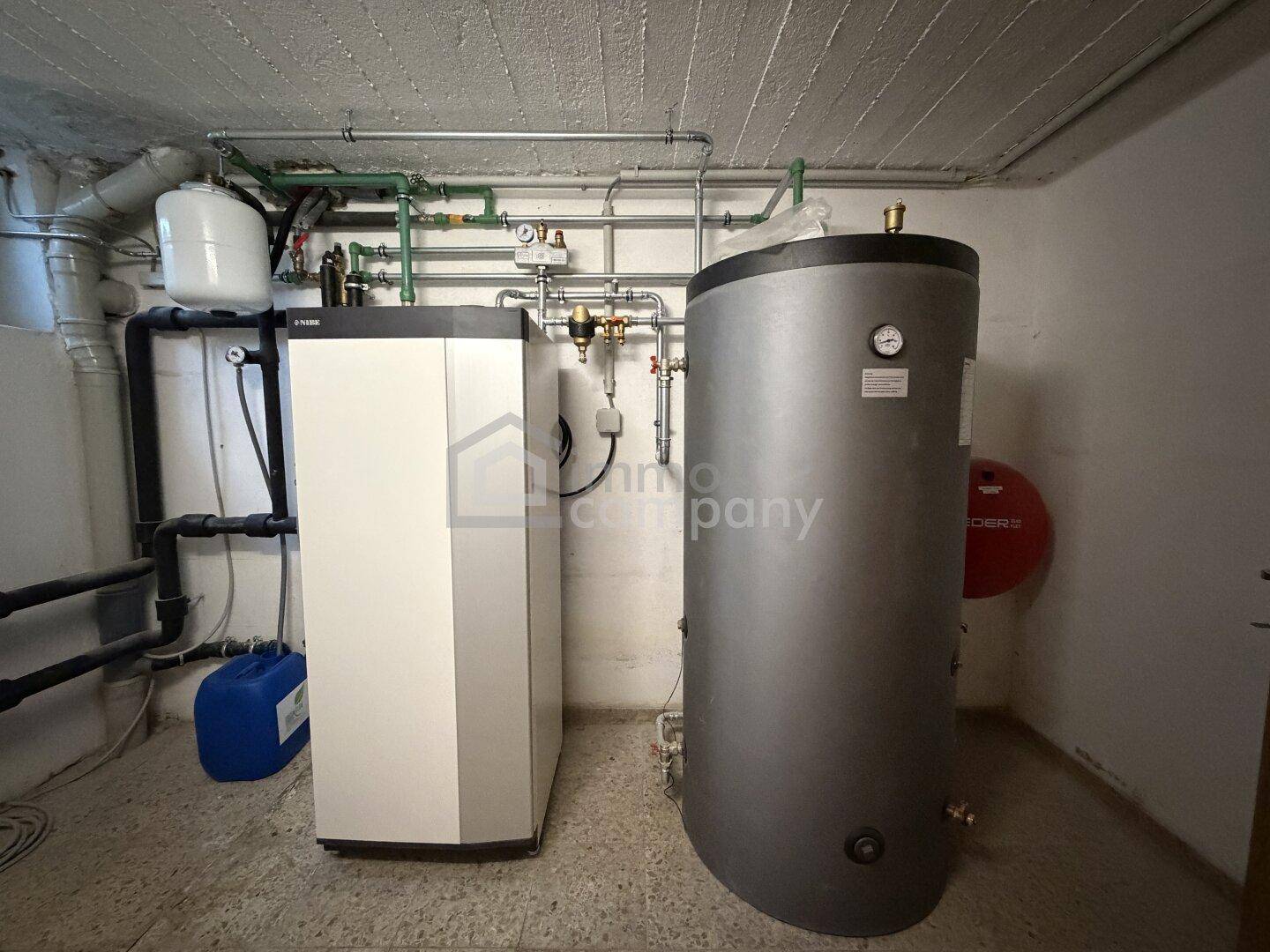 Heizungsraum im Keller mit moderner Heizungsanlage und Warmwasserspeicher in gutem Zustand.