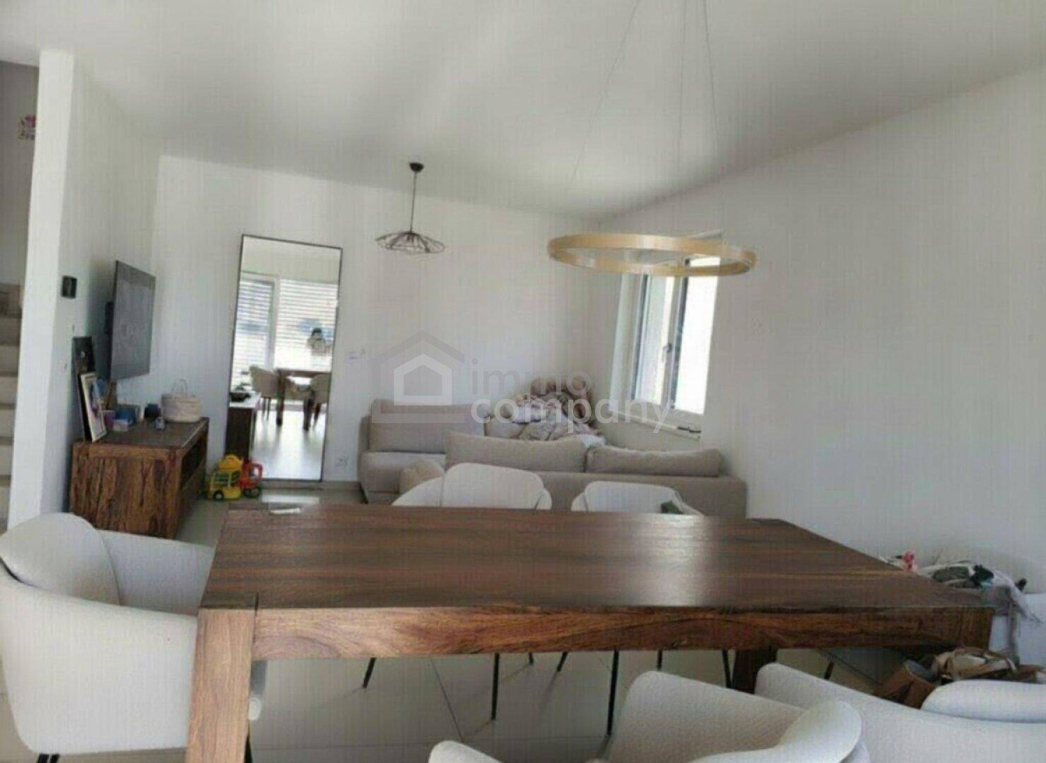 Offener Wohn- und Essbereich mit großem Holztisch, bequemer Couch und viel Tageslicht.