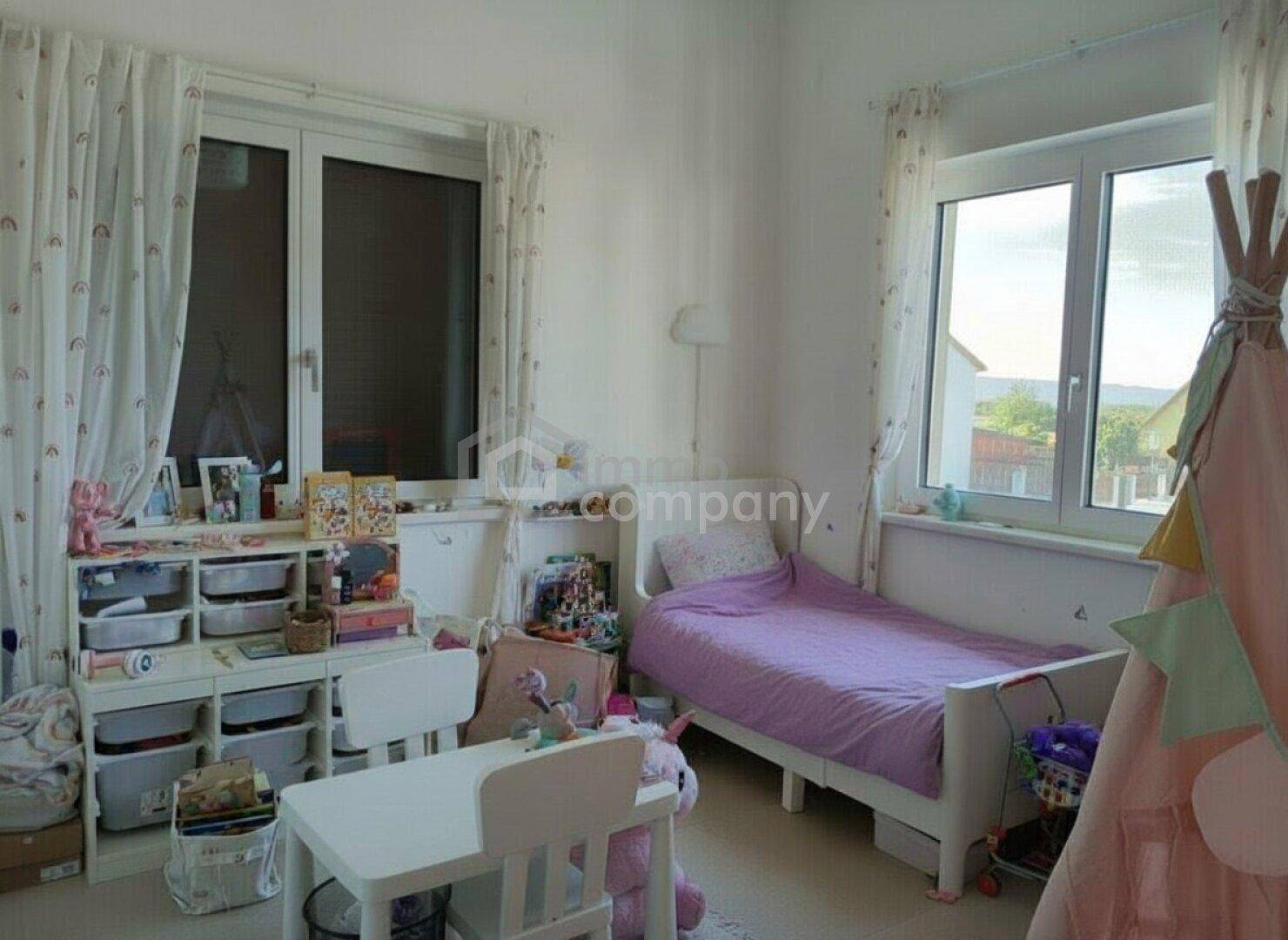 Freundliches Kinderzimmer mit Einzelbett, Schreibtisch und großen Fenstern für viel Tageslicht.