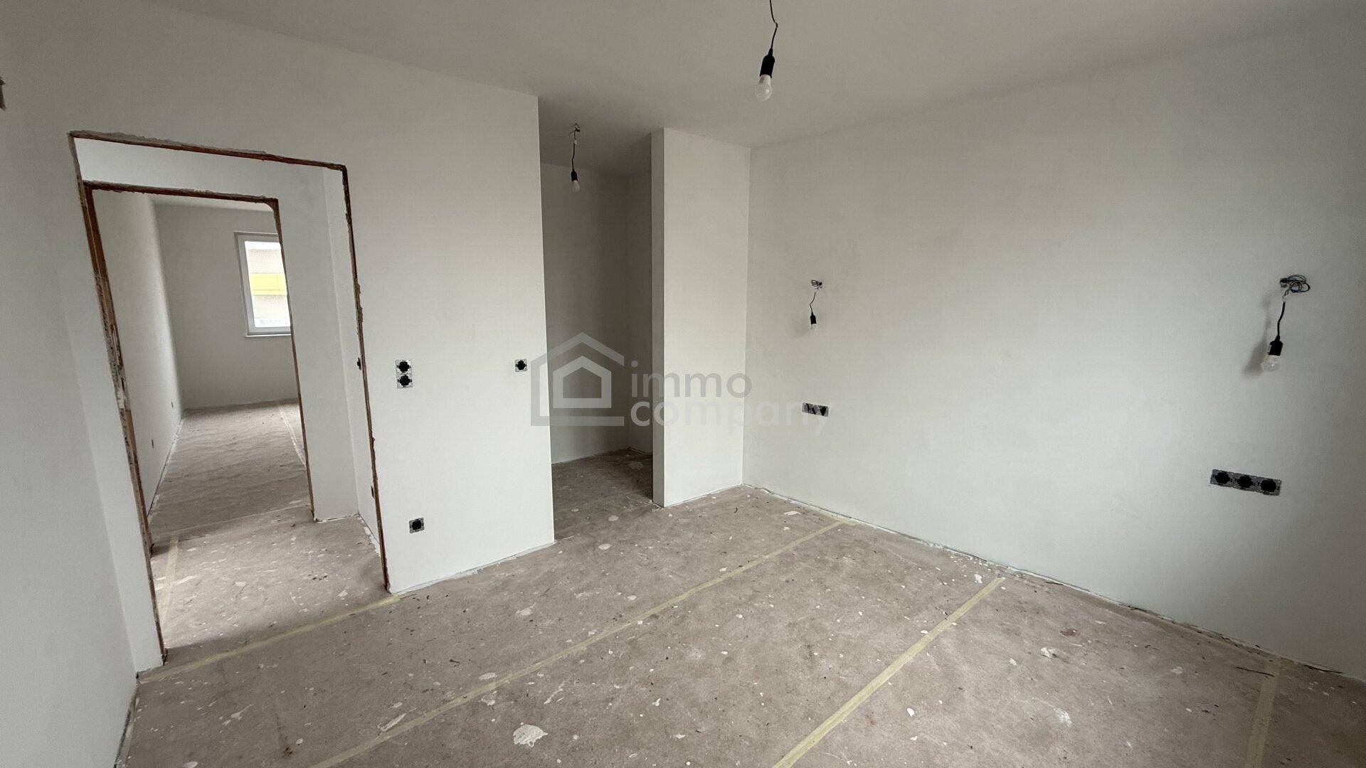 Unfertiges Zimmer mit weißen Wänden und Türrahmen, bereit für den Innenausbau.