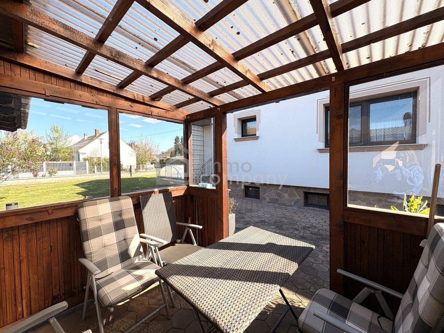Gemütlicher, verglaster Terrassenbereich mit Sitzgelegenheiten und Blick in den Garten.