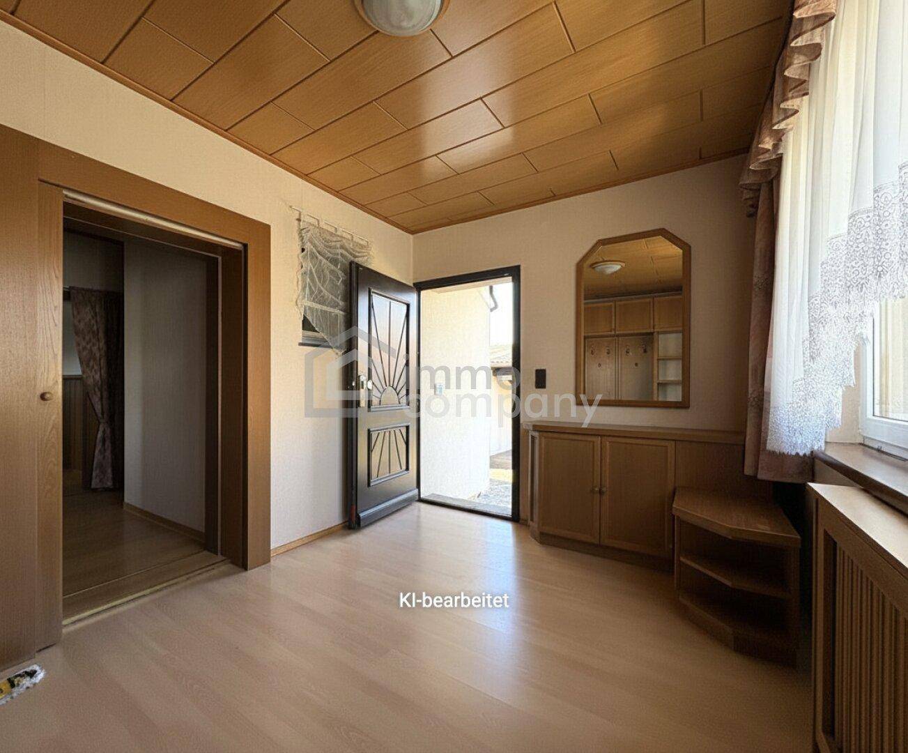 Heller Eingangsbereich mit Holzdecke, Garderobe und Blick auf die Haustür.