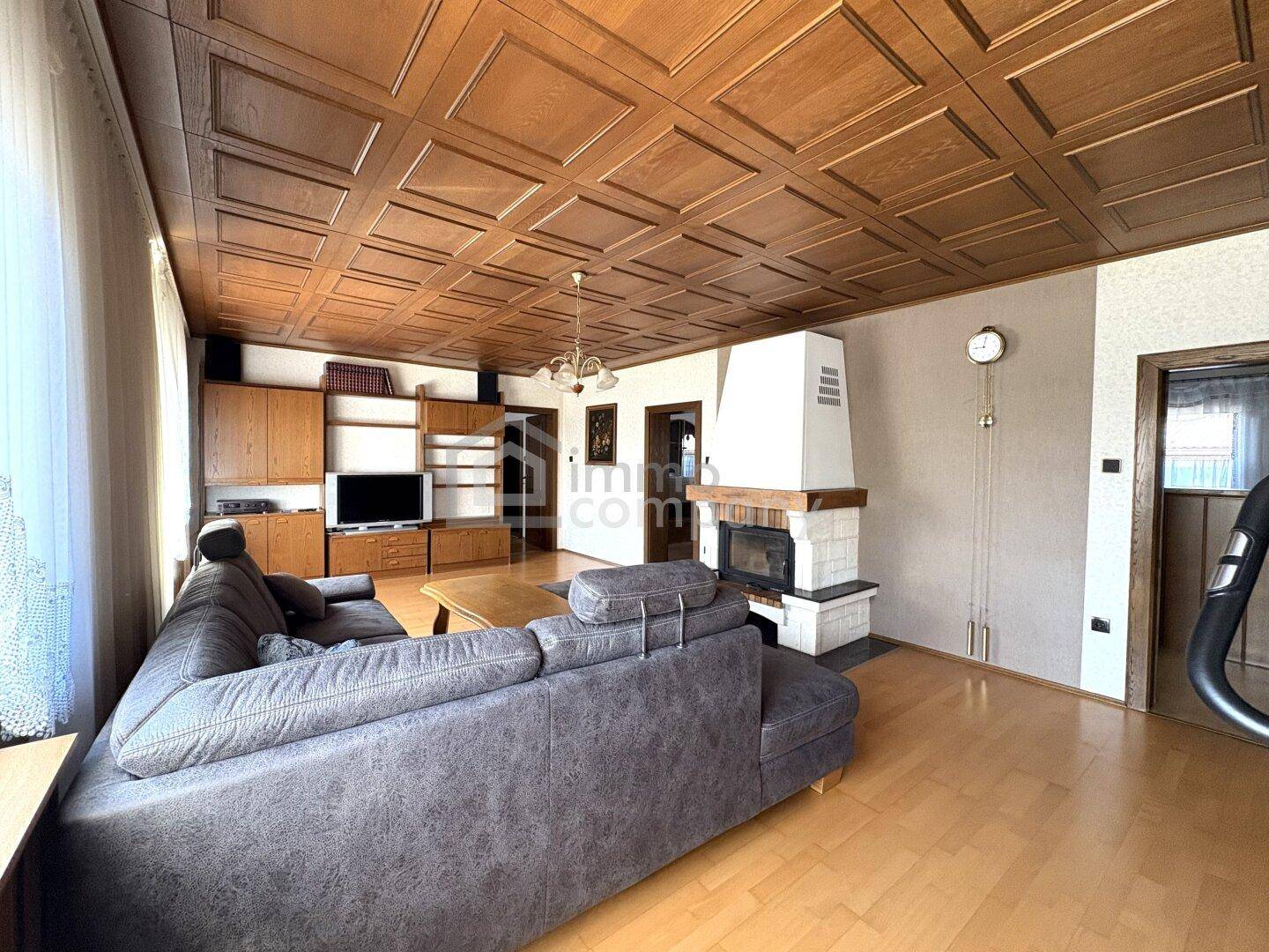 Geräumiges Wohnzimmer mit Kamin, Holzdecke und bequemer Sofagarnitur für entspannte Abende.