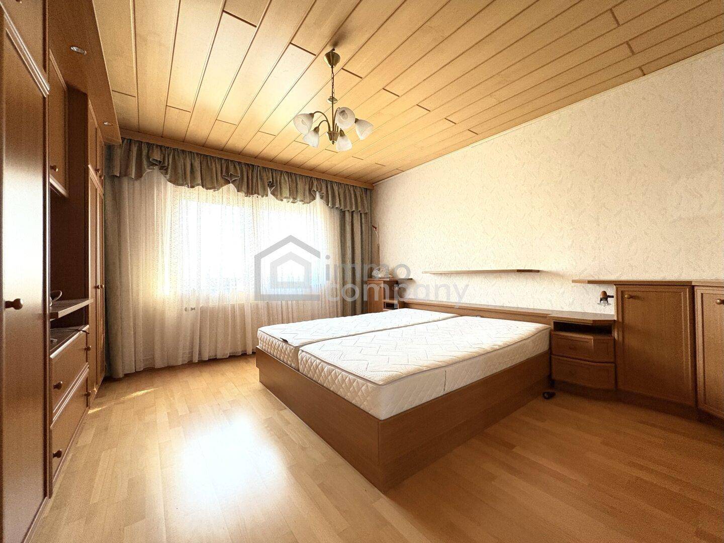 Helles Schlafzimmer mit Doppelbett, Holzdecke und großen Fenstern für viel Tageslicht.