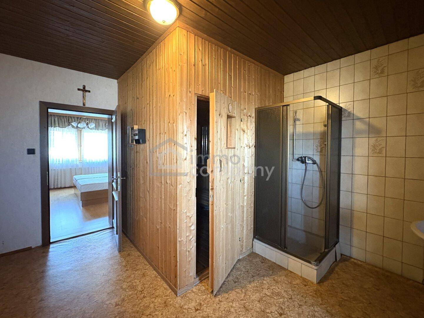 Raum mit Holzsauna und Duschkabine, ideal für Entspannung und Wellness im eigenen Zuhause.