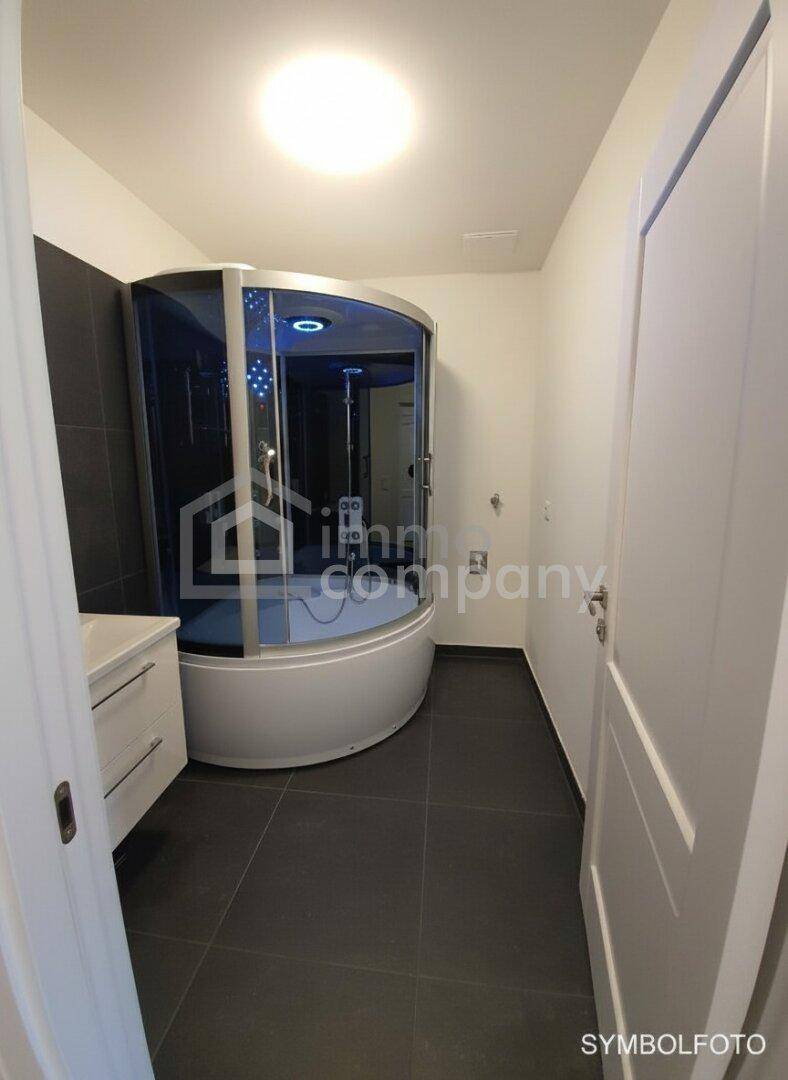 Modernes Badezimmer mit einer geräumigen Duschkabine und dunklen Fliesen.