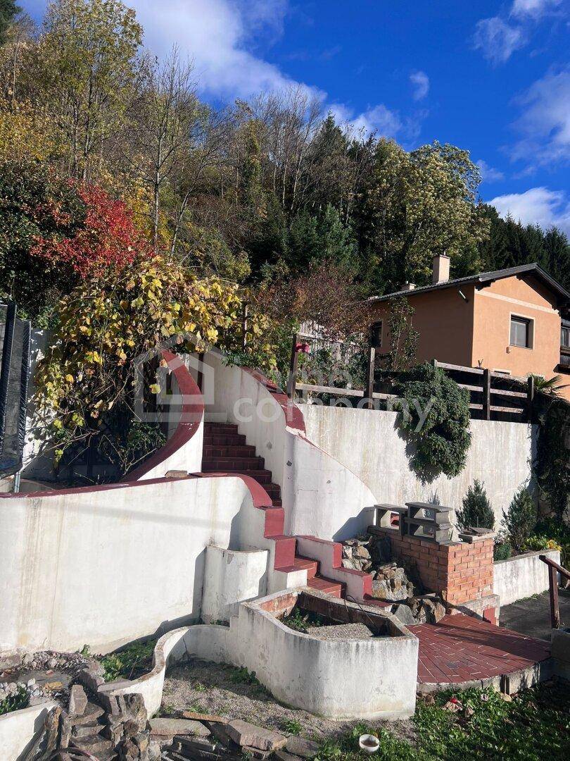 Terrassierter Gartenbereich mit roten Treppen und Steinmauern.