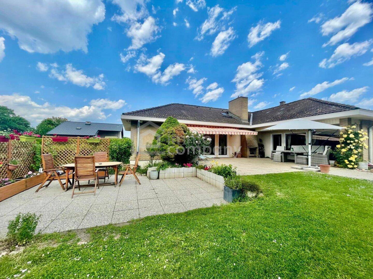 Geräumige Terrasse mit Gartenmöbeln und Markise, umgeben von gepflegtem Grün.