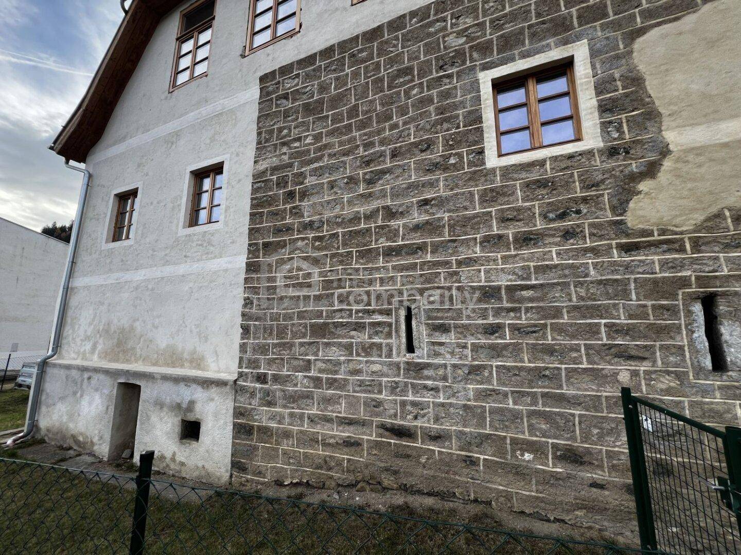Detailansicht der historischen Steinmauerfassade des Gebäudes mit kleinen Fenstern.