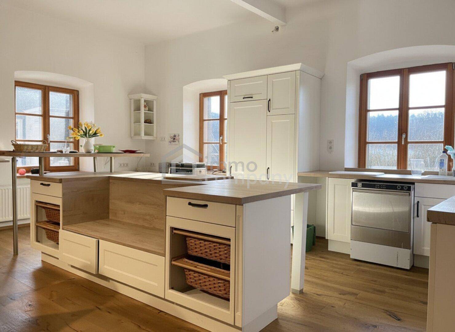 Helle, geräumige Küche mit Holzboden, weißen Schränken und viel natürlichem Licht.