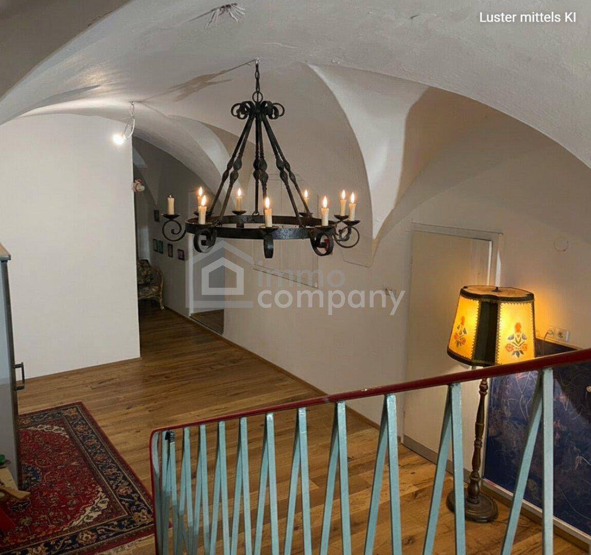 Historischer Treppenaufgang mit Gewölbedecke und schmiedeeiserner Lampe.