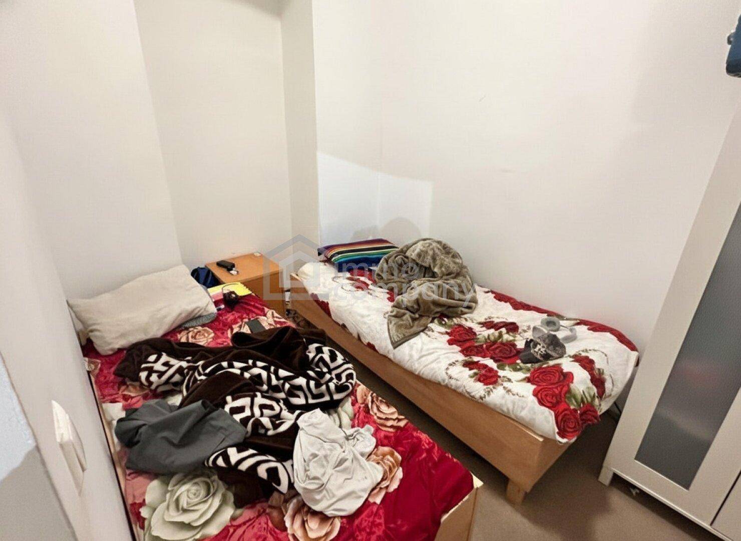Kleines Schlafzimmer mit zwei Einzelbetten und einfacher Einrichtung.