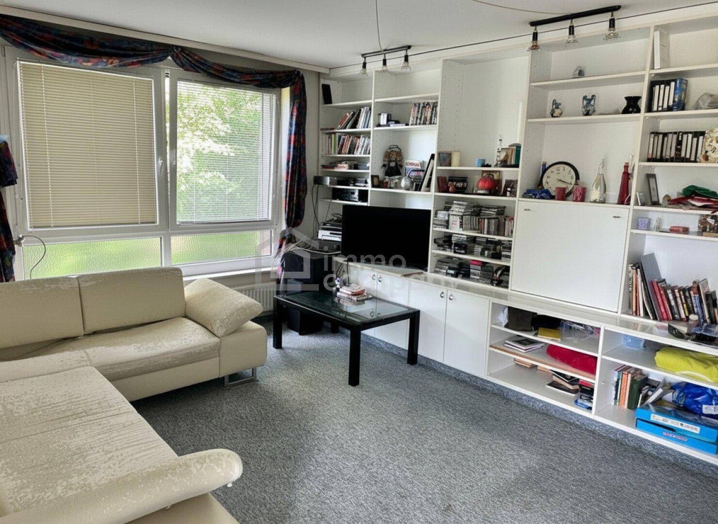 Wohnzimmer mit großem Ecksofa, Bücherregal und Fernseher, das viel Stauraum bietet.