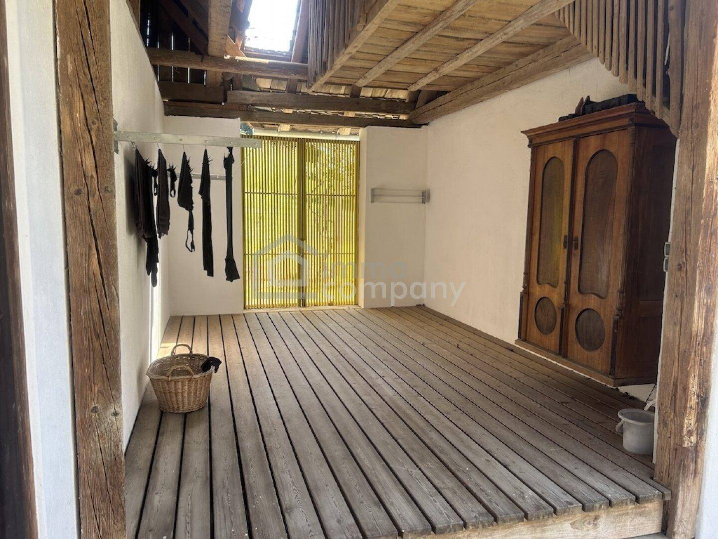 Offener Raum mit Holzboden, sichtbaren Balken und viel natürlichem Licht.