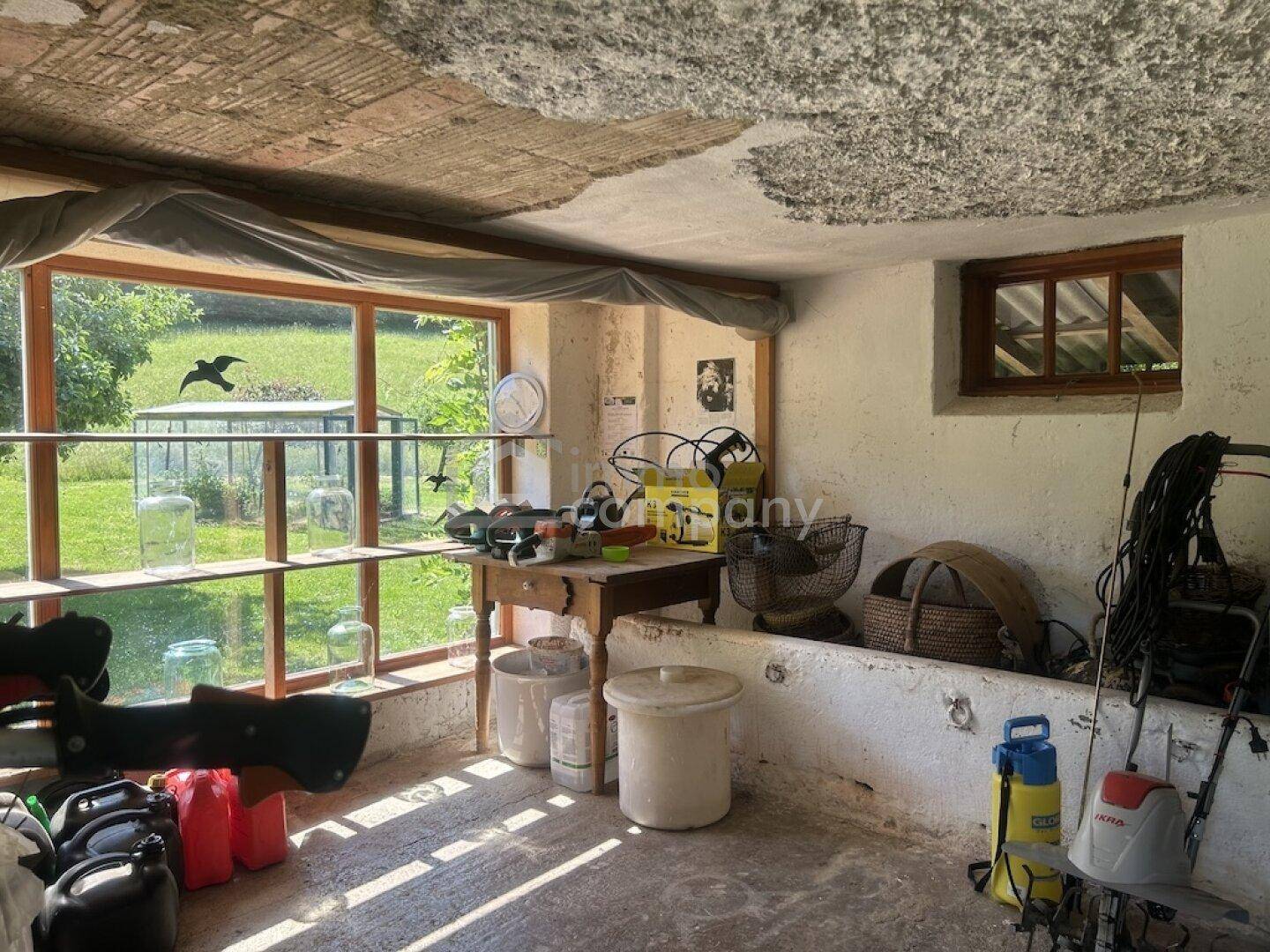 Praktischer Abstellraum mit großen Fenstern, die den Blick auf den Garten und ein Gewächshaus freigeben.