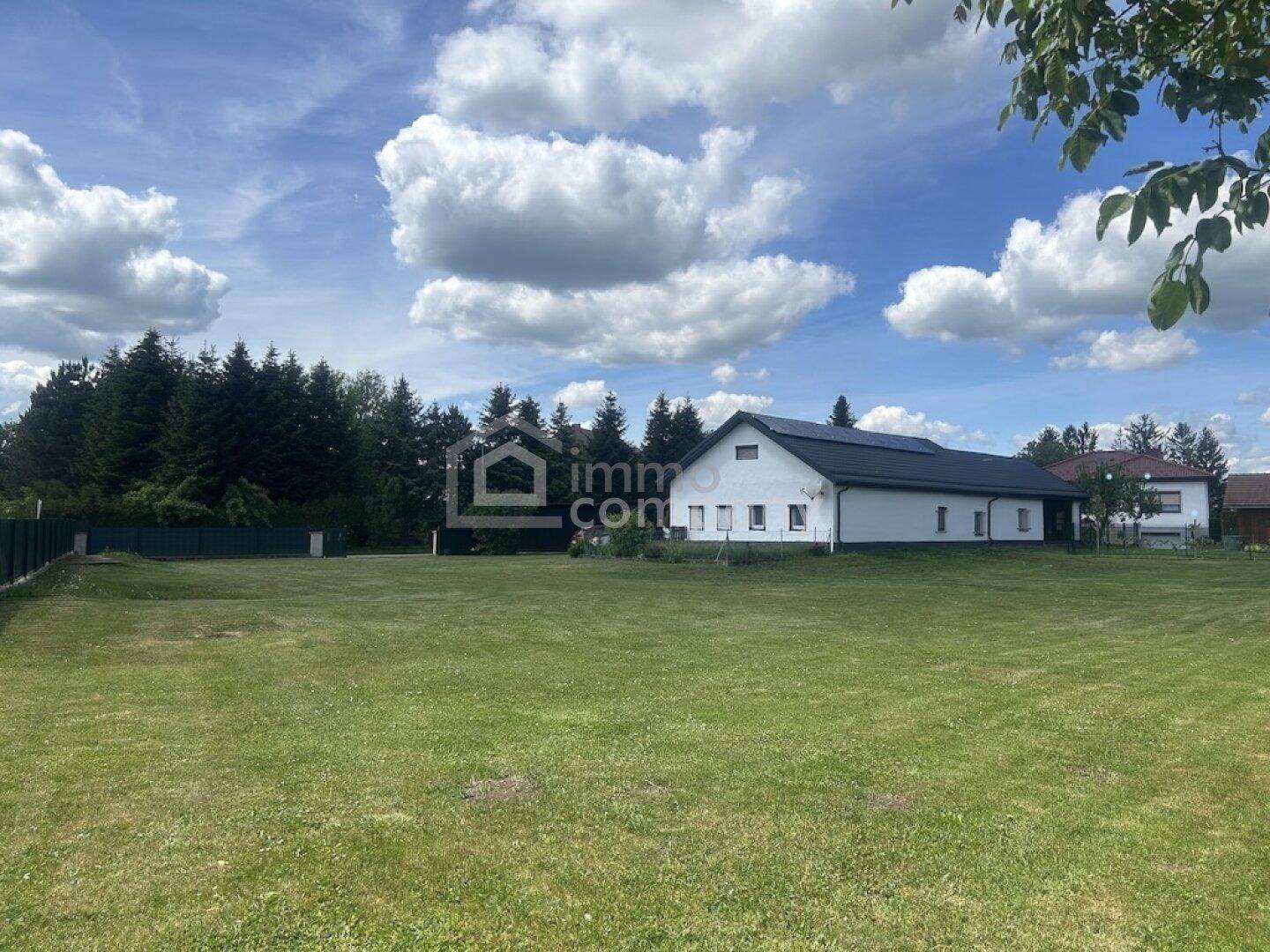 Weitläufiges Grundstück mit großem Rasen, Bäumen und dem Einfamilienhaus im Hintergrund, ländliche Idylle.
