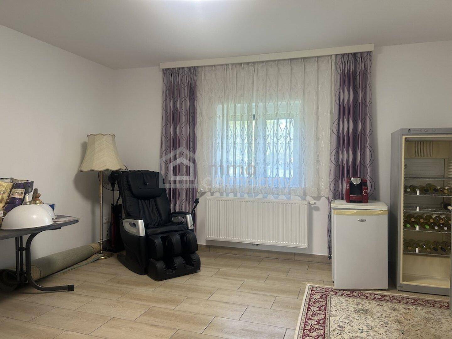 Heller Wohnraum mit Massagesessel, Weinkühler und großem Fenster, ausgestattet mit Fliesenboden.