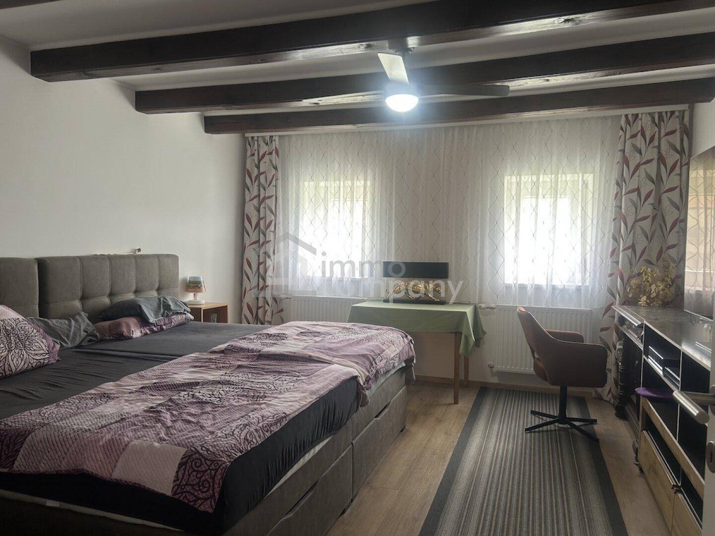 Geräumiges Schlafzimmer mit Doppelbett, Deckenventilator und Holzboden, hell und einladend.