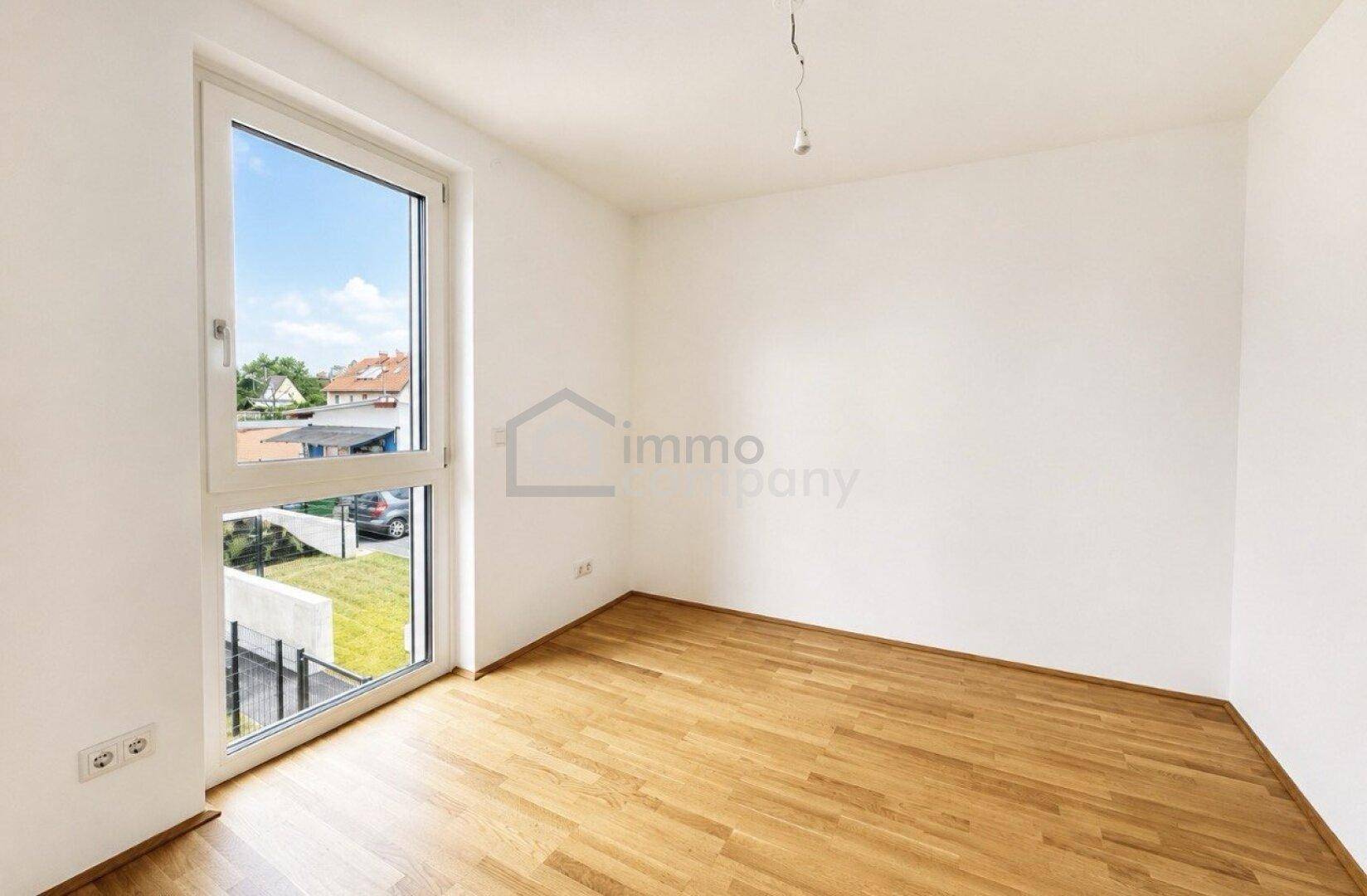 Helles Schlafzimmer mit großem Fenster, Blick ins Grüne und auf die umliegende Nachbarschaft.