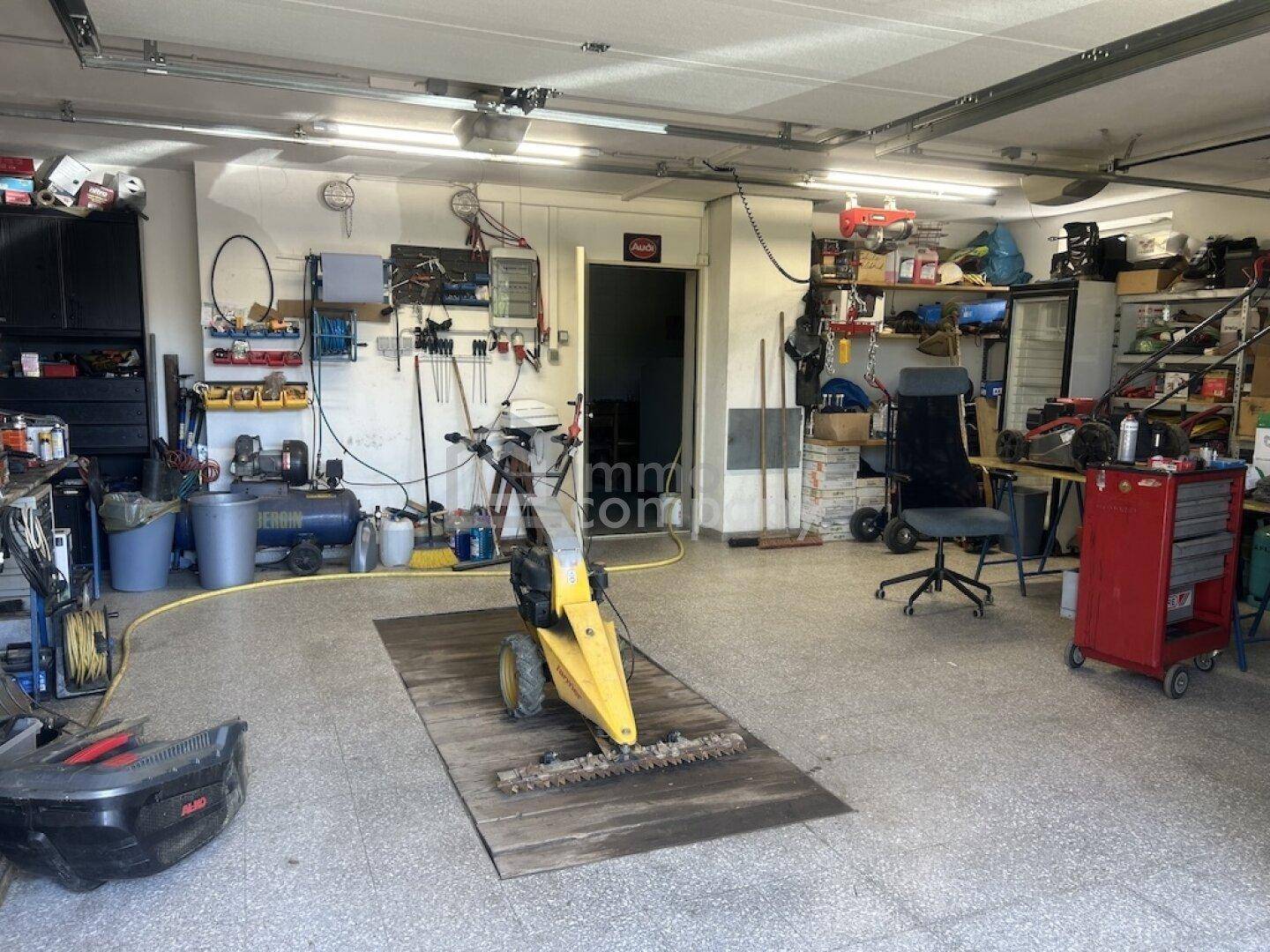 Geräumige Garage, die als Werkstatt genutzt wird, mit verschiedenen Werkzeugen und Geräten.