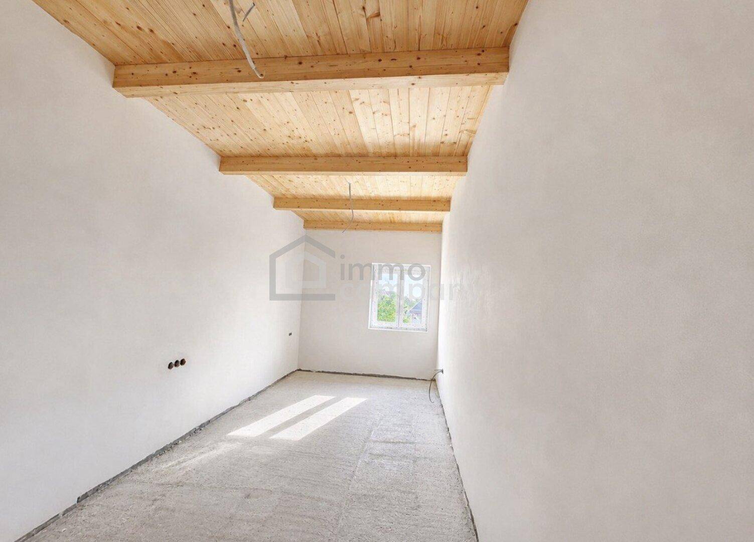 Leeres Zimmer mit Holzbalkendecke und Fenster, bietet viel Potenzial.