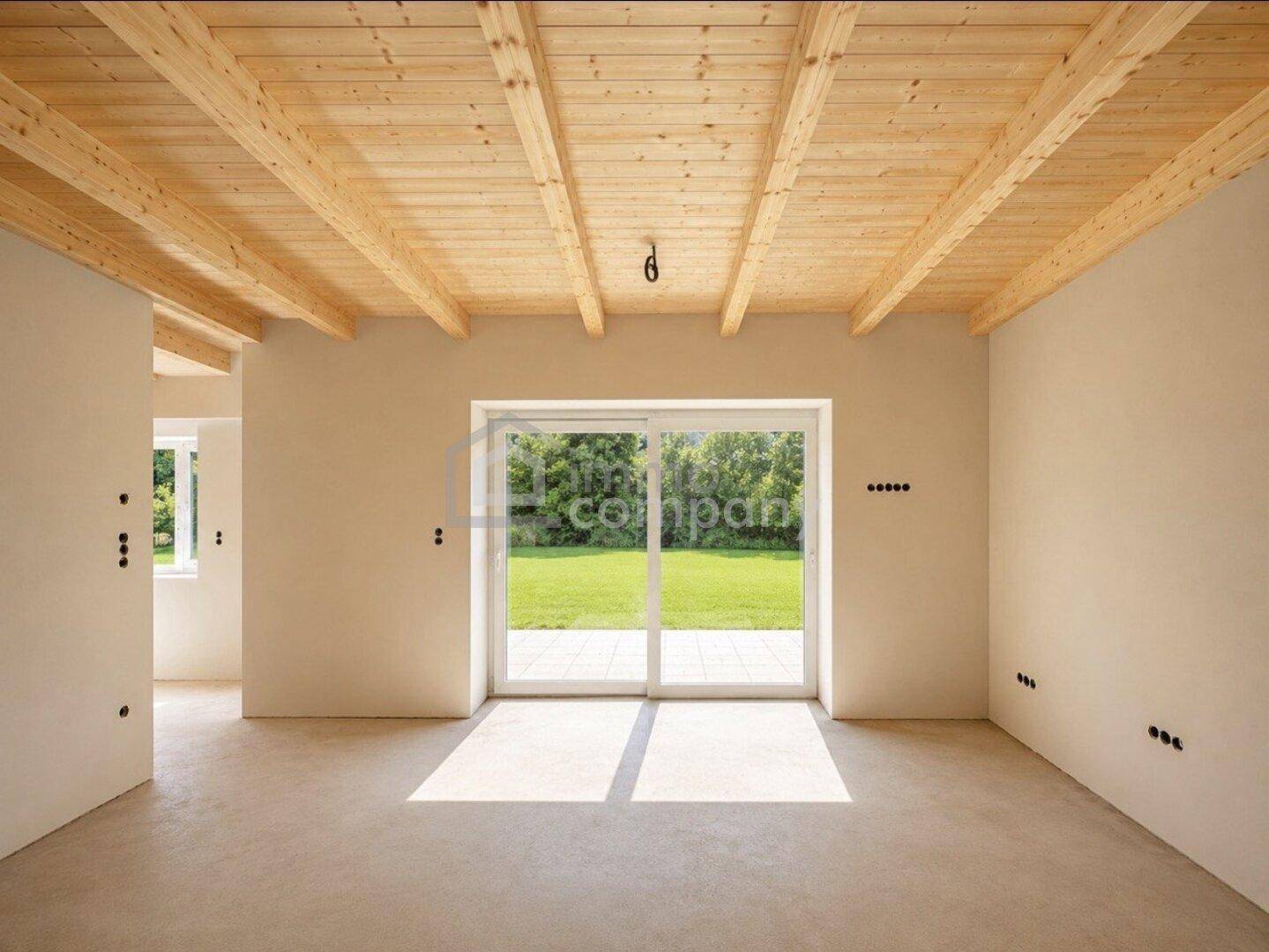 Heller Wohnraum mit Holzbalkendecke und großer Schiebetür zum Garten.