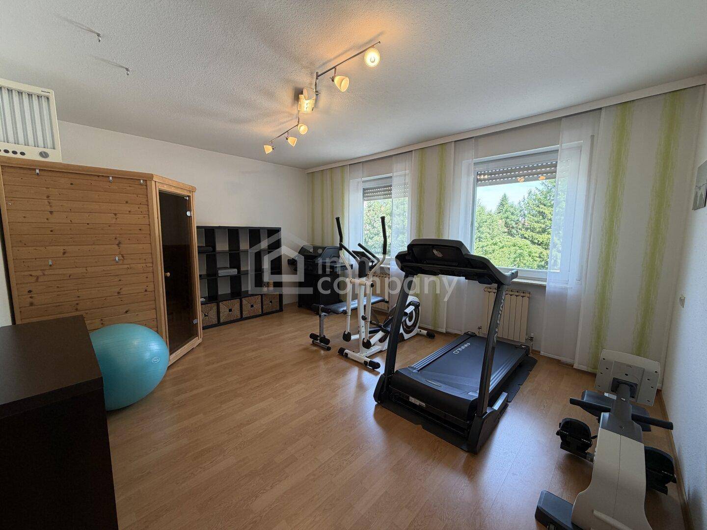Fitnessraum mit Laufband, Crosstrainer und einer integrierten Sauna.