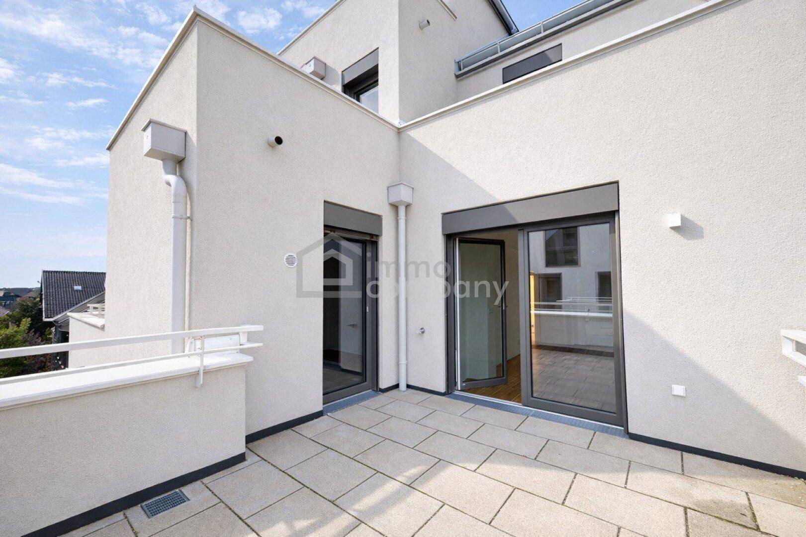 Geräumige, gepflasterte Terrasse mit Zugang zum Innenbereich und moderner Architektur.
