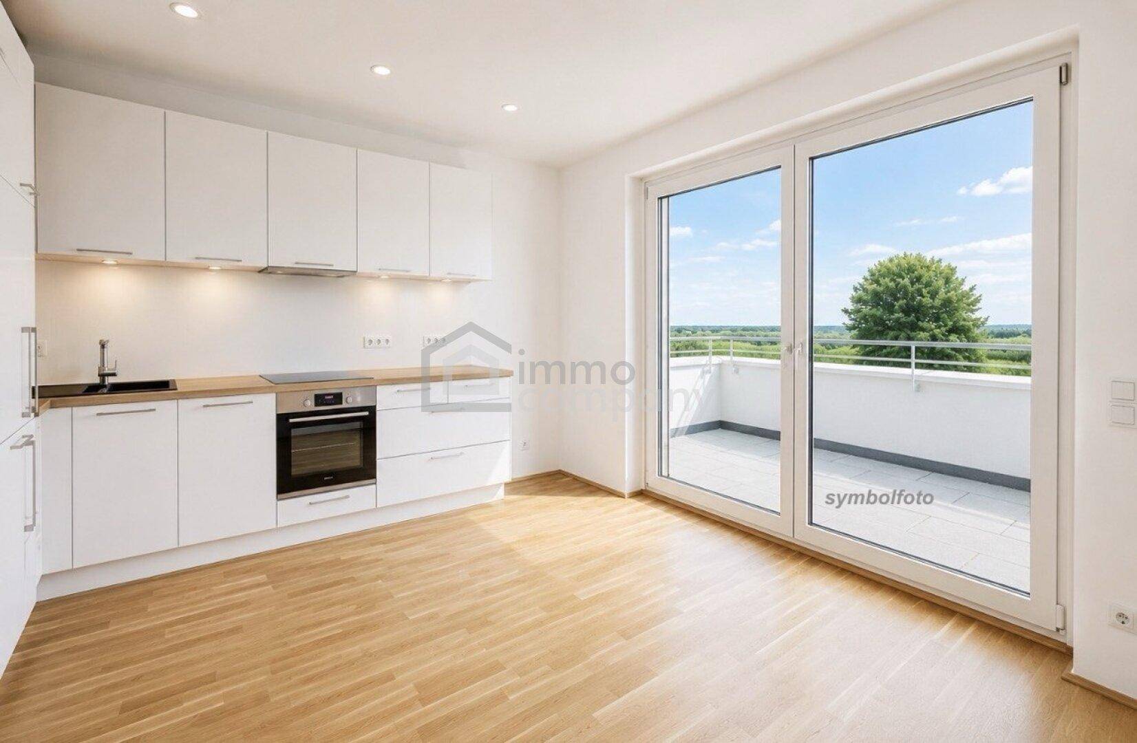 Helle Einbauküche mit weißen Schränken, Holz-Arbeitsplatte und Zugang zu einem sonnigen Balkon mit Weitblick.