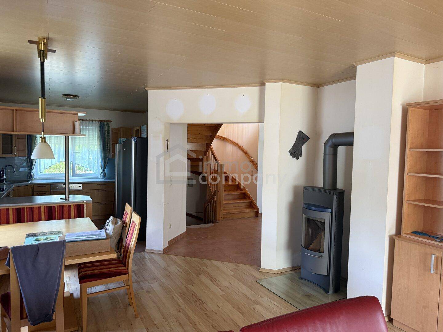 Offener Wohn-Essbereich mit Kaminofen, Holzboden und Blick in die Küche.