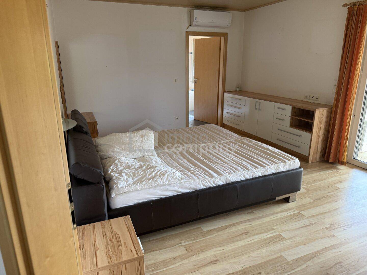 Schlafzimmer mit Doppelbett, Holzfußboden und Zugang zu einem Balkon oder Terrasse.