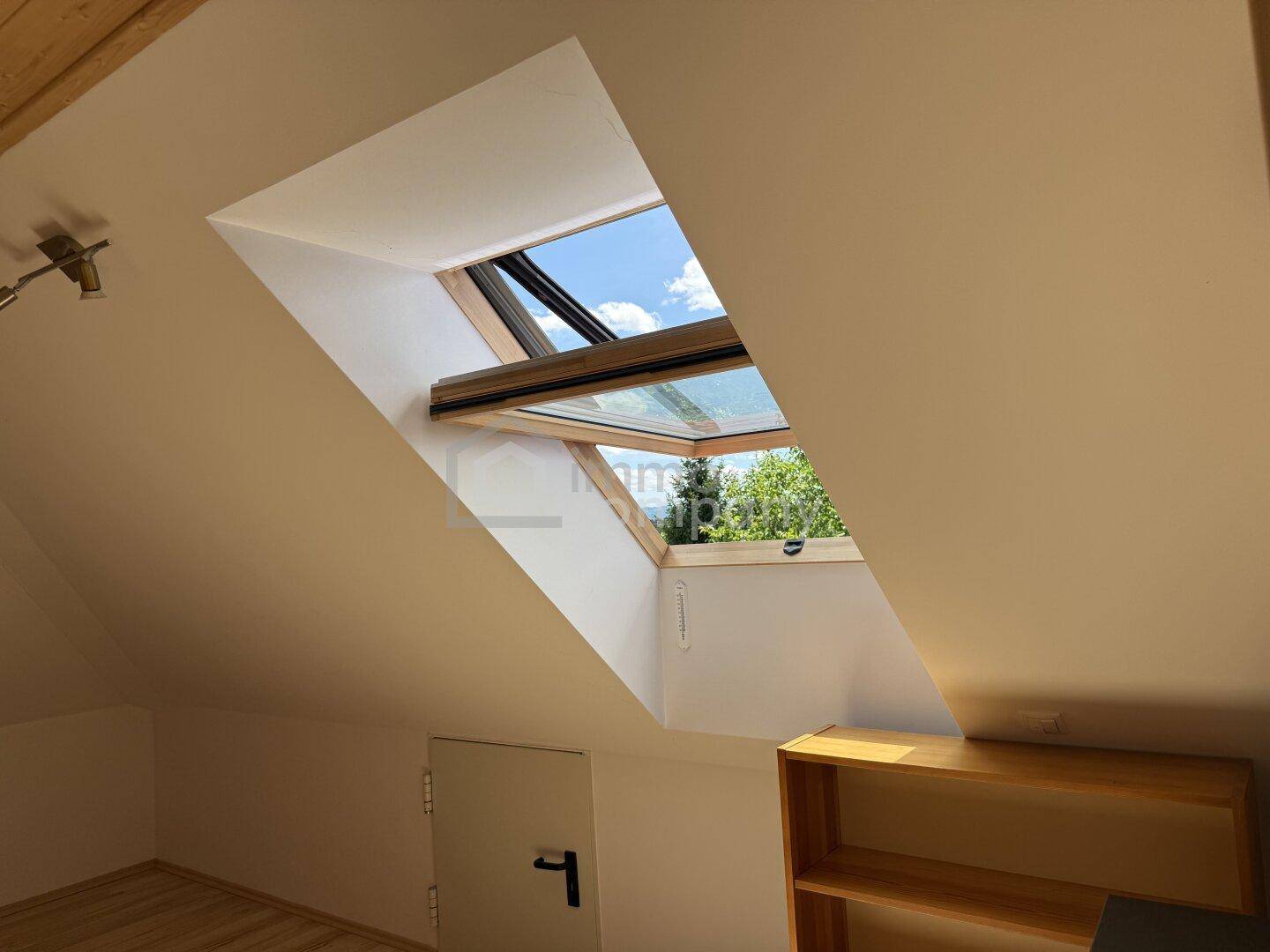 Heller Dachbodenraum mit großem Dachfenster, das viel Tageslicht hereinlässt.