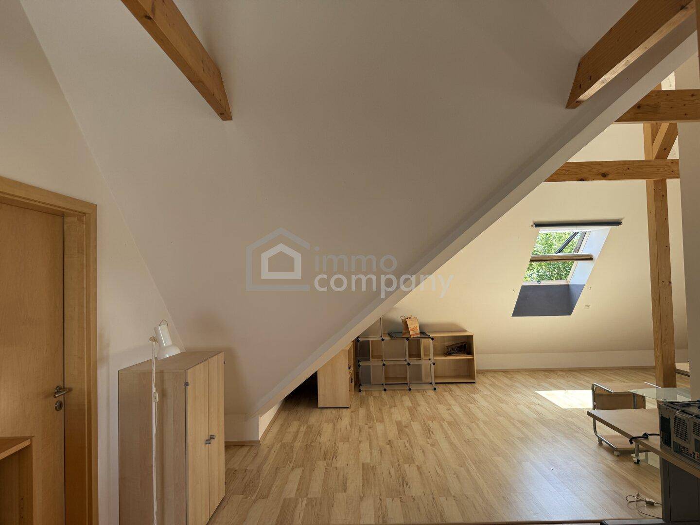 Geräumiger Dachbodenraum mit schrägen Wänden, Holzboden und Dachfenster.