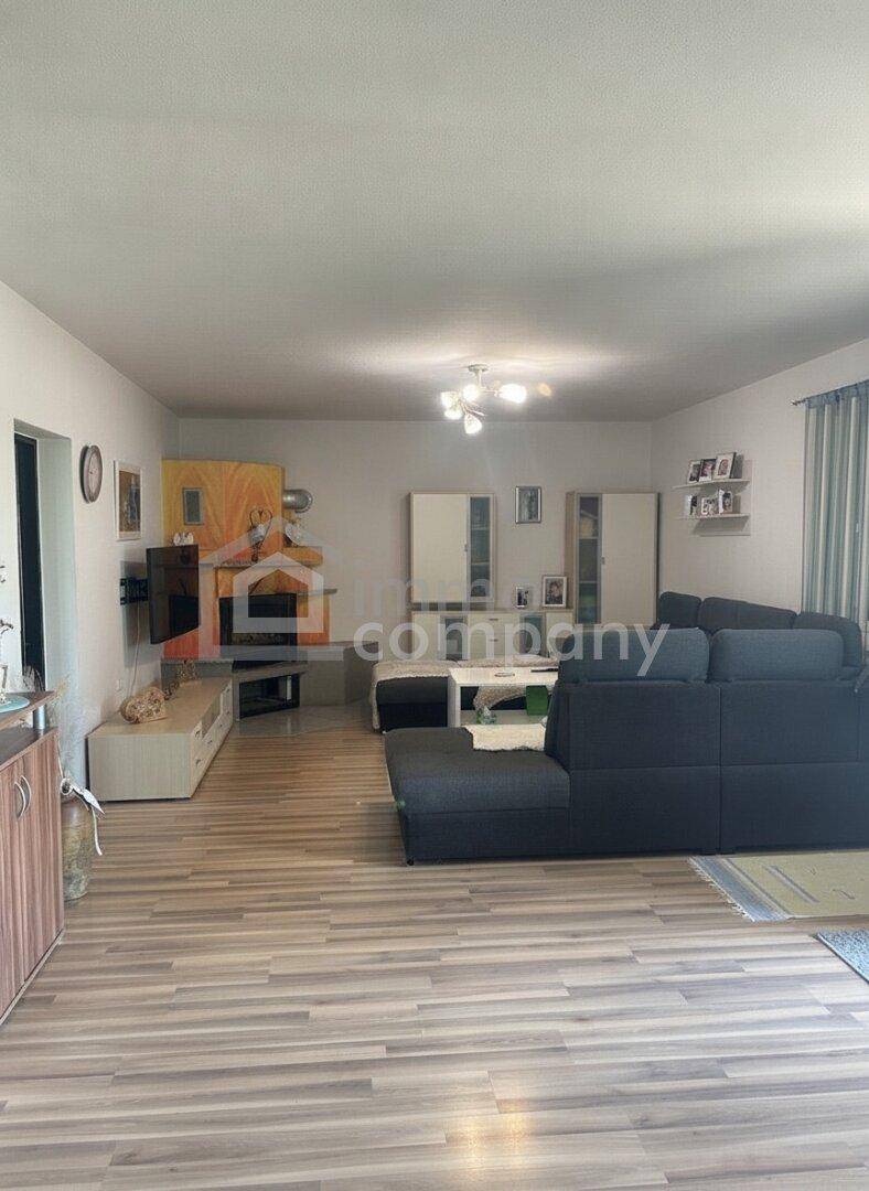 Heller Wohnbereich mit Laminatboden, großem Ecksofa und modernen Möbeln in neutralen Farben.