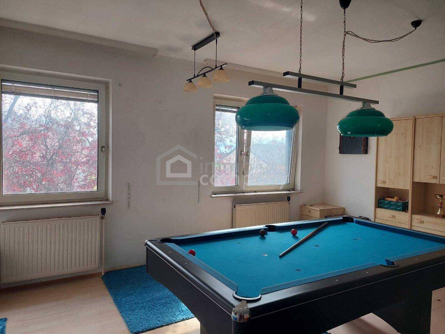 Geräumiger Hobbyraum mit Billardtisch und großen Fenstern, ideal für Freizeitaktivitäten.