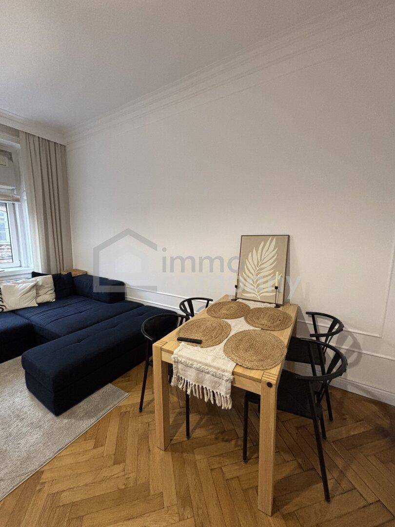 Offener Wohn-Essbereich mit Holztisch, Stühlen und Blick auf das Sofa.