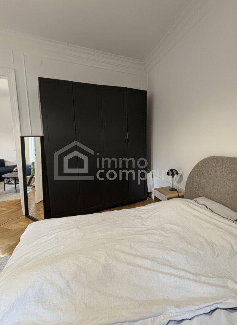 Schlafzimmer mit großem schwarzen Kleiderschrank und Parkettboden.