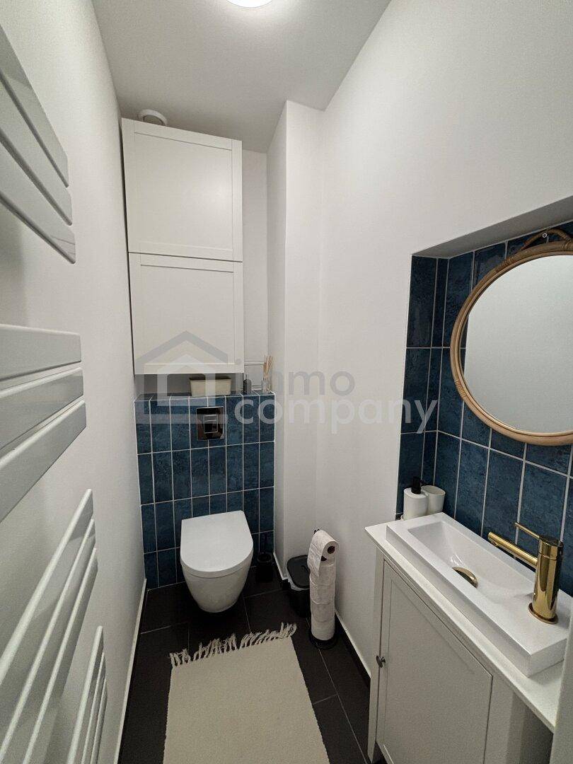 Gäste-WC mit wandhängender Toilette, Waschbecken und beheiztem Handtuchhalter.