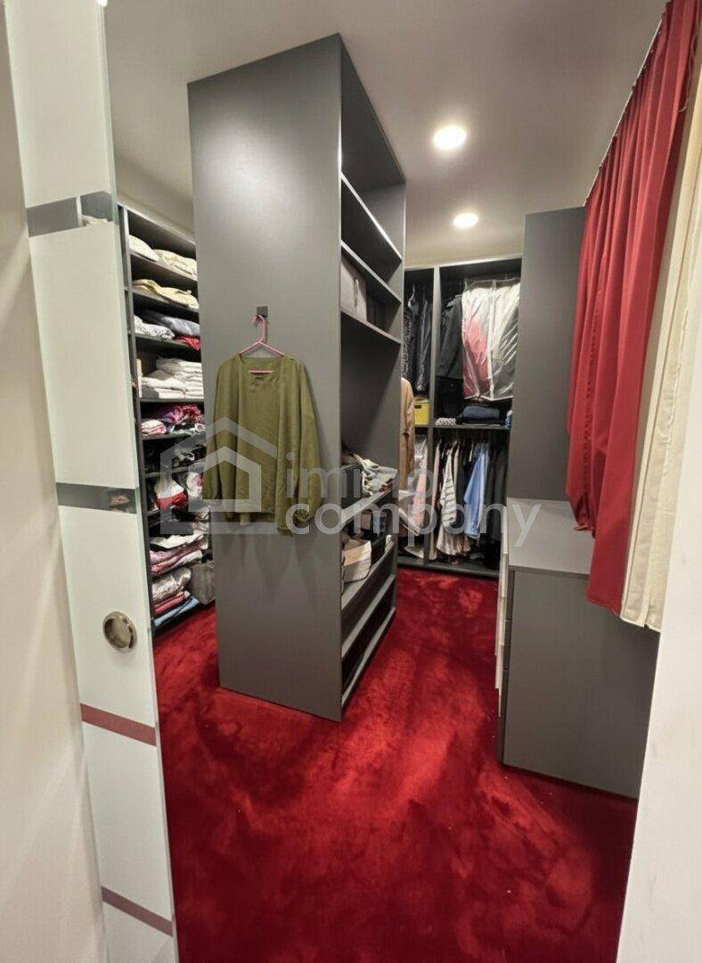 Geräumiger begehbarer Kleiderschrank mit grauen Einbauschränken und rotem Teppichboden.