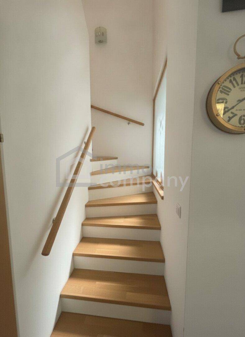 Helle Holztreppe mit weißen Setzstufen und schlichten Holzhandläufen.