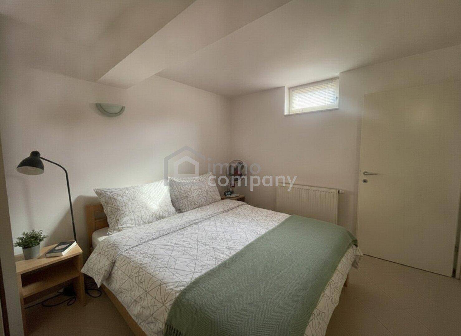 Schlafzimmer im Untergeschoss mit kleinem Fenster und schlichter Einrichtung.